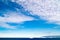 Greenlandic blue sky with altocumulus clouds over dark blue Arctic Ocean with iceberg, Greenland