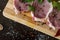 greens, seasonings and meat on a cutting board. three steaks of pork, pepper, garlic, salt.