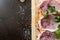 greens, seasonings and meat on a cutting board. three steaks of pork, pepper, garlic, salt.