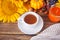 Greeting autumn card. Composition with pumpkin, autumn leaves, sunflower, cup of tea, plaid and berries on the wooden background.