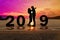 Greeting card 2019 happy new years. Silhouette young couple embrace each other with sunset at tropical beach. People