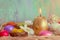 Greeting card Easter burning golden candle and chocolate eggs in colored foil. Blurred background and glowing bokeh. Copy space.