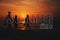 Greeting card with the inscription time of summer. Silhouettes of three men walking along the beach by the sea