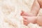 Greeting card or invitation for baby shower. Closeup of baby`s feet on a beige textured plaid. copyspace