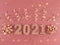 Greeting card of New Year 2021. Glittered figures, stars, bows and ribbons on a light pink background.