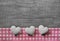 Greeting card: three white and pink checked hearts on wooden grey shabby chic background.