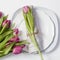 Greeting card for Valentine`s day. Decoration of the wedding table. On a plate a napkin with a tulip, beautifully tied.
