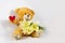 A greeting composition with a funny character in the form of a teddy bear with a bouquet of pale yellow tulips and a red heart  on