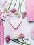 Greeting flat lay with pastel pink envelope, flowers and accessories on white desk , top view