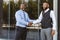 Greeting and handshake of two afro american businessmen partner against the backdrop of a modern building exterior