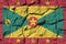 Grenada flag depicted in paint colors on old stone wall closeup. Textured banner on rock wall background