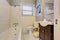 Grey antique elegant bathroom with white tub and dark brown cabinet.