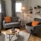 Grey armchair next to lamp in orange vintage living room interior with sofa next to cabinet