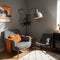 Grey armchair next to lamp in orange vintage living room interior with sofa next to cabinet