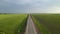 Grey asphalt road with automobile between green fields