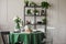 Grey and black wooden chairs at round table with green tablecloth,plates, mugs and wine glasses