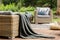 Grey blanket on rattan sofa near armchair with pillows on wooden