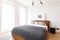 Grey blanket on wooden bed in white bright bedroom interior with