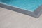 Grey brown corner edge of a swimming pool blue water