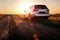 Grey car stay on dirt road at sunset