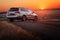 Grey car stay on dirt road at sunset