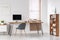 Grey chair at desk with computer monitor in minimal workspace in