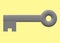A grey colored key with a ring for key chain hooking against a light yellow backdrop