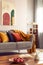 Grey comfortable sofa with orange blanket and colorful pillows