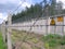 Grey concrete fence at hazardous radioactive waste facility with barbed wire with warning signs caution radiation