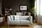 Grey couch with pillows in bright vintage living room interior with plants and poster. Real photo