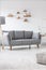 Grey couch in simple bright living room interior with pouf and l