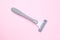 Grey disposable plastic razor blade for removing unwanted hair for woman on pink background