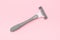 Grey disposable plastic razor blade for removing unwanted hair for woman on pink background