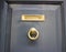 Grey door with a gold doorknocker and mailbox