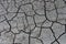 Grey dried and cracked ground earth background. Closeup of dry fissure dark ground. erosion