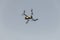 Grey drone with digital camera. Drone hovering in blue sky. Radio control helicopter.