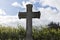 Grey grave stone cross standing alone in Cemetery, blue sky background