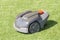 Grey green autonomous electric lawn mower in garden cut grass