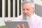 Grey-haired bearded man reading on a tablet