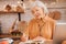 Grey-haired beautiful elderly lady in orange blouse making notes