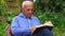 Grey haired man in hoodie enjoys reading book in garden