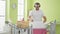 Grey-haired man listening to music hanging clothes on clothesline at laundry room