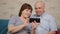Grey haired pensioner is helping by his aged wife with new smartphone app.