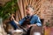 Grey-haired pensive painter with paintbrush sitting in armchair in studio