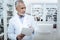 Grey-haired positive pharmacist in a white coat making a revision