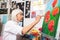 Grey-haired retired artist painting red poppies with gouache