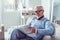 Grey-haired retired man smiling while reading positive local news