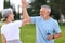 Grey-haired spouses giving high five to each other with beaming smiles outside during work out