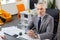 Grey-haired strict man in grey costume being concentrated at work