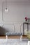 Grey hallway interior with a bench, lamp and flower in a vase on a stand. Real photo. Place for your poster